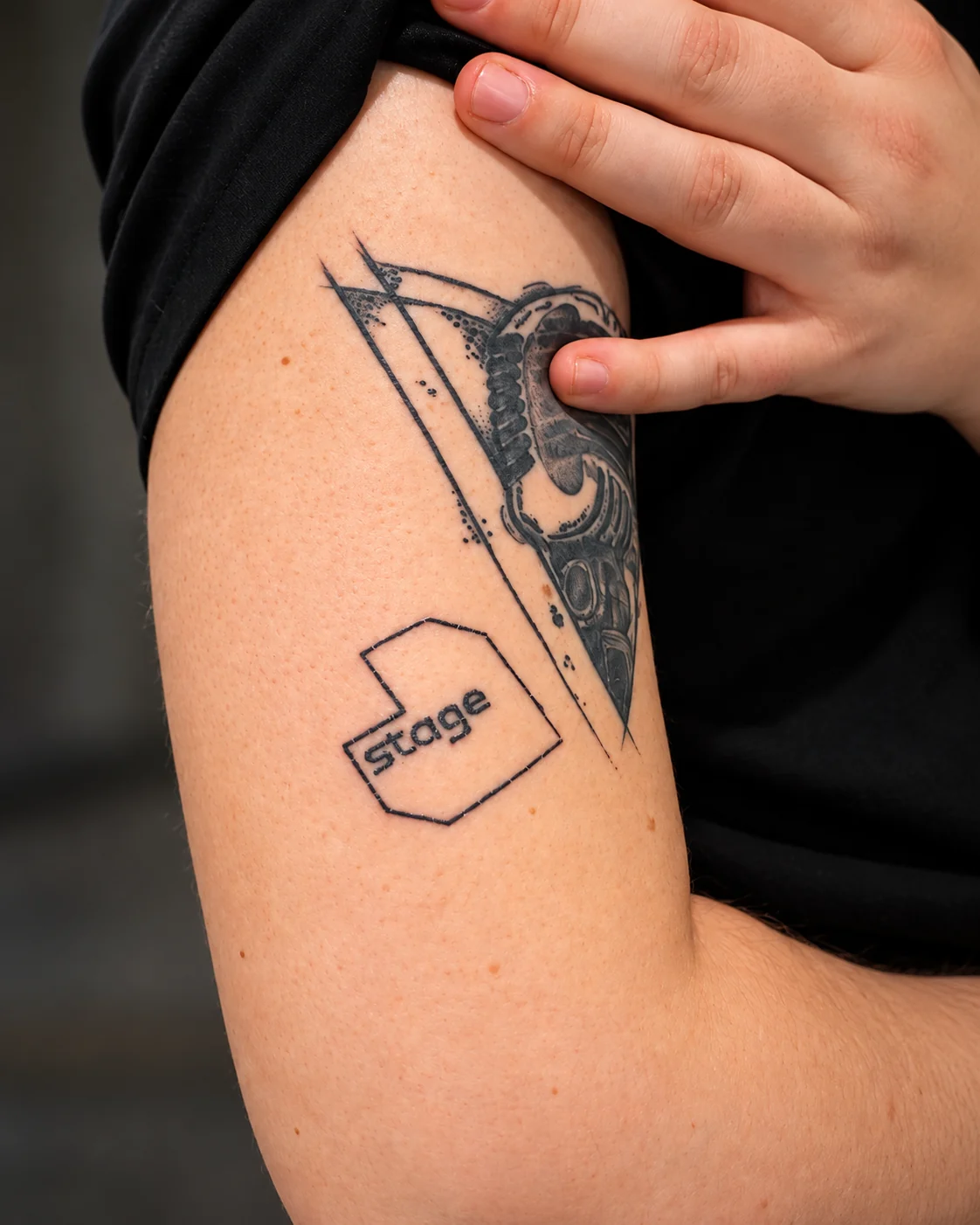 A permanent tattoo of the Stage logo on a shoulder